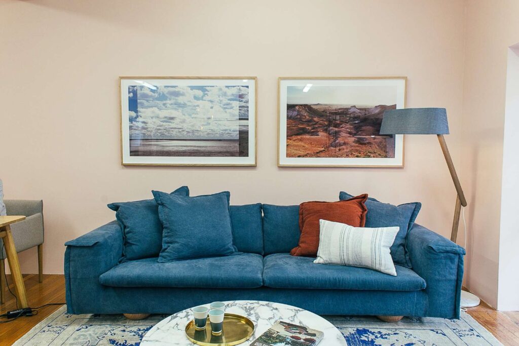 Blå sofa i stue. Inrettet med 2 malerier på væggen