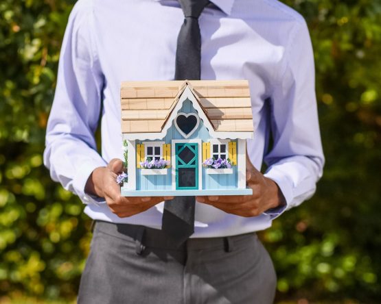 Mand holder lille hus i sine hænder fordi han skal sælge en bolig